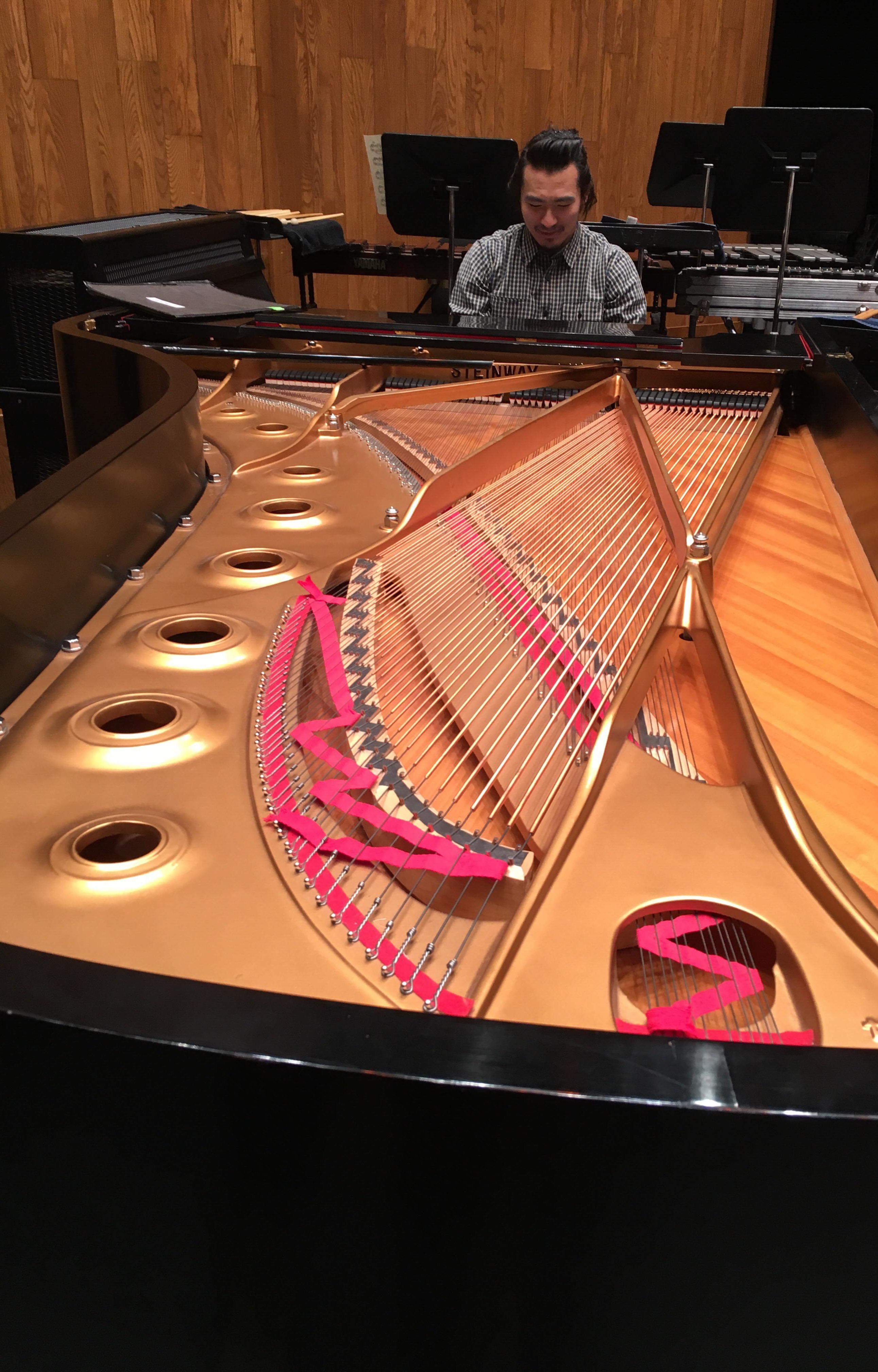 Sebastian at Orch Piano FullScale A longways shot of Sebastian playing a grand piano with no lid on it in orchestra